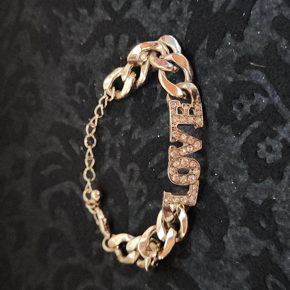 Gold toned chain link with Rhinestone letters.